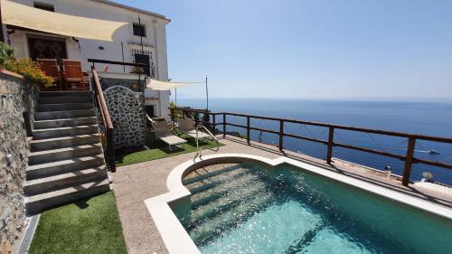 a swimming pool on the side of a house with the ocean at Villa Sunrise. Pool and seaview in Amalfi Coast in Conca dei Marini