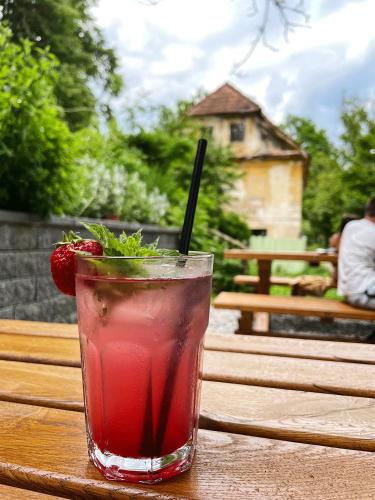 a drink sitting on a wooden table with a strawberry at Vintage tent at the Lovsin Estate in Metlika