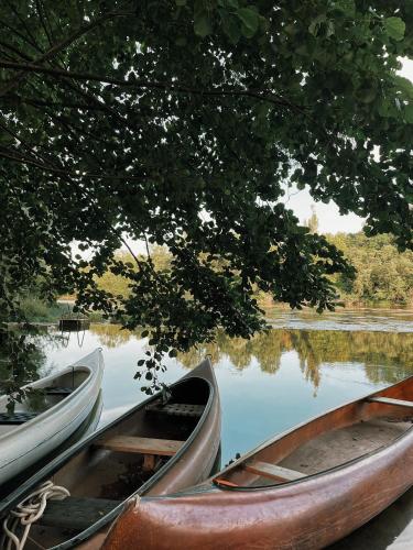 three boats sitting in the water under a tree at Vintage tent at the Lovsin Estate in Metlika