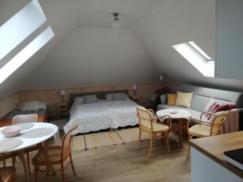 a attic bedroom with a bed and tables and chairs at Pension Brusenka in Bystřice pod Hostýnem
