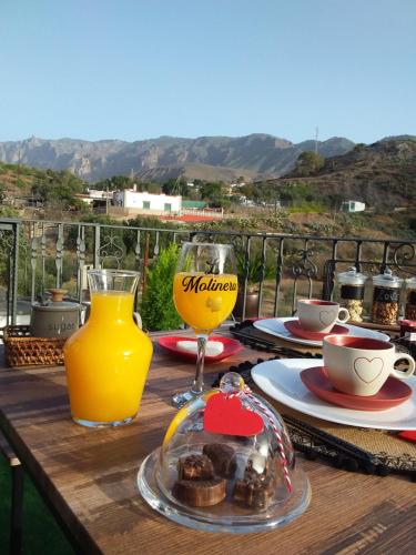 a wooden table with a glass of orange juice and a plate of food at Romantic Casa Rural La Molinera in Santa Lucía