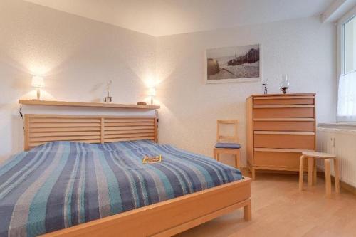 グラール・ミューリッツにあるWellenkieker-Graal-Mueritzのベッドルーム1室(木製ヘッドボード付きのベッド1台、ドレッサー付)