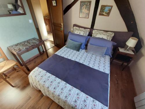 - une chambre dotée d'un grand lit avec des draps et des oreillers bleus dans l'établissement Longère Villariane, à Naveil