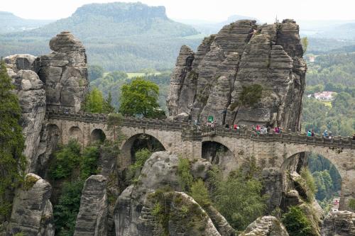 a group of people walking over a bridge on a mountain at Ferienwohnungen Elbjuwel in Rathen