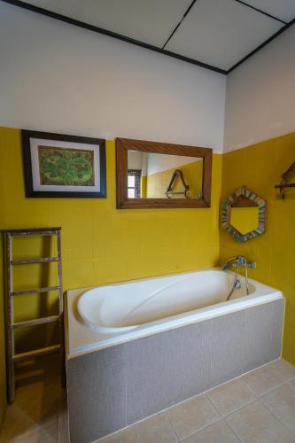 a bath tub in a bathroom with a yellow wall at Varinda Resort in Lamai