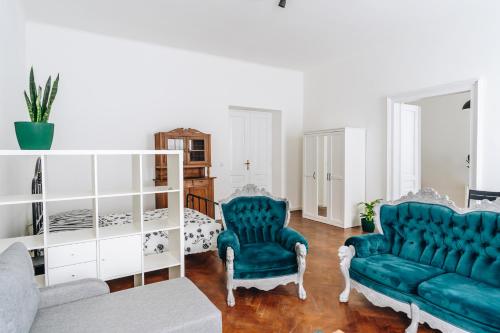 salon z 2 niebieskimi krzesłami i łóżkiem w obiekcie Podzamcze 24 Apartments w Krakowie