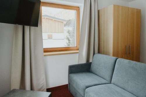 a living room with a blue couch and a window at Gästehaus Kolp in Sankt Anton am Arlberg