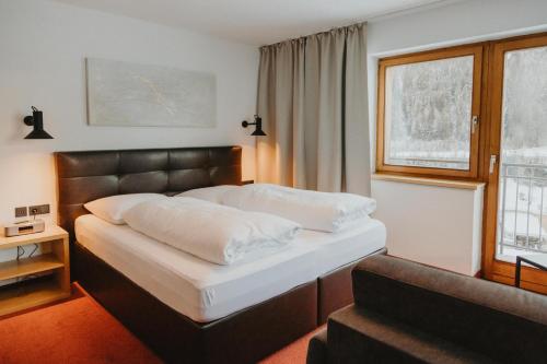 a bedroom with a bed with a leather headboard and a window at Gästehaus Kolp in Sankt Anton am Arlberg