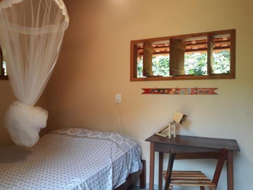 ein Schlafzimmer mit einem Bett, einem Tisch und zwei Fenstern in der Unterkunft Chalé confortável em Alter do Chão in Alter do Chao