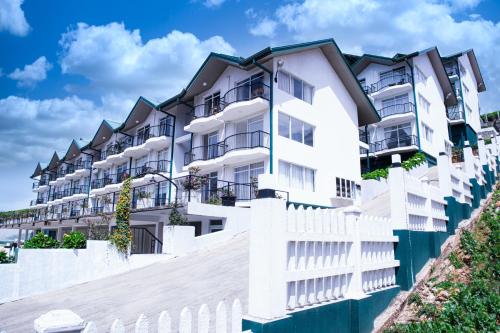 a white apartment building with a white fence at Moon Plains Luxury Apartments in Nuwara Eliya