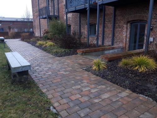 a brick walkway in front of a building with a bench at Pension in der Alten Mälzerei in Angermünde