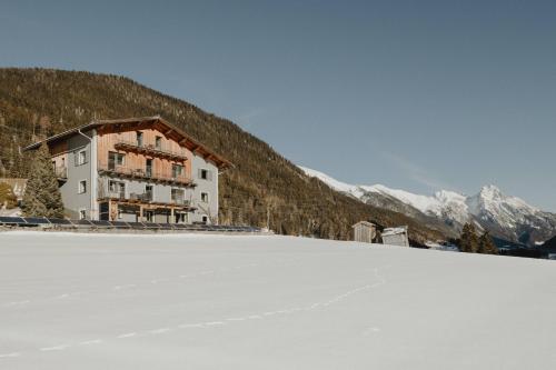 a building on a snow covered slope in front of a mountain at Gästehaus Kolp in Sankt Anton am Arlberg