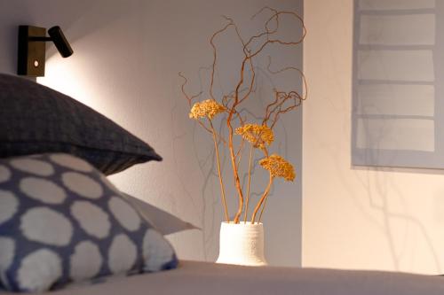 a vase with yellow flowers in it sitting on a bed at Casa del Borgo "Aria & Acqua" sul Lago Maggiore in Maccagno Inferiore