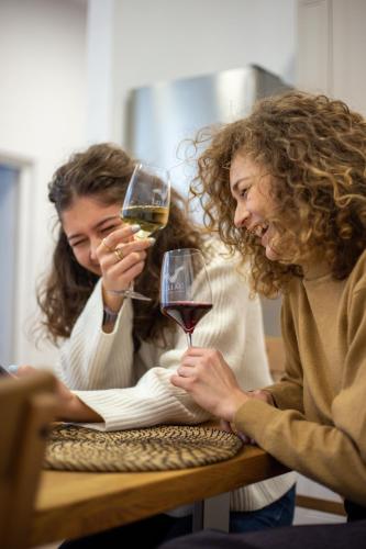 two women sitting at a table with glasses of wine at Zakarias Apartments in Miercurea-Ciuc