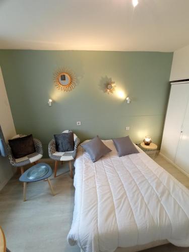 une chambre avec un grand lit blanc et deux chaises dans l'établissement Studio confort proche cure et port de plaisance, à Rochefort