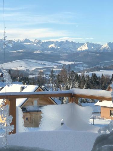 a snow covered balcony with a view of snow covered mountains at Velo Apartamenty in Czorsztyn