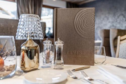 a table with wine glasses and a box on it at Tevini Dolomites Charming Hotel in Commezzadura