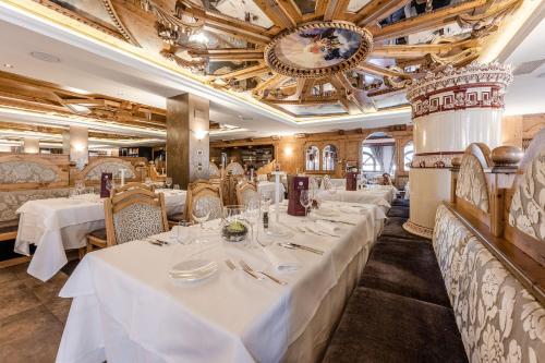 a restaurant with white tables and chairs and a clock at Tevini Dolomites Charming Hotel in Commezzadura