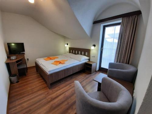 sypialnia z łóżkiem, 2 krzesłami i telewizorem w obiekcie Hotel Flora w Beszeniowej