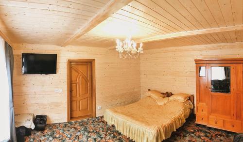 a bedroom with a bed and a flat screen tv at Вершина Карпат in Krasnik