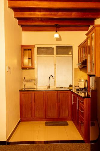 a kitchen with wooden cabinets and a sink and a window at Moon Plains Luxury Apartments in Nuwara Eliya