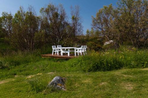 two white benches sitting on a wooden table in a field at Cozy cabin with stunning view in Alstad