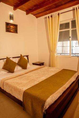 a bedroom with a large bed with a window at Moon Plains Luxury Apartments in Nuwara Eliya