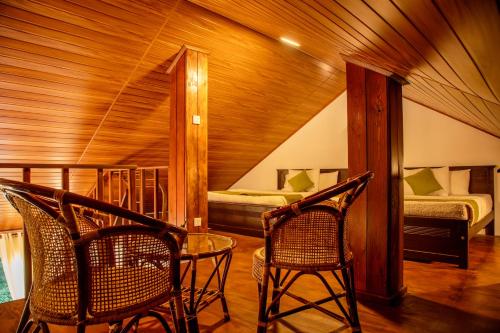 two chairs and a table in a room with two beds at Moon Plains Luxury Apartments in Nuwara Eliya