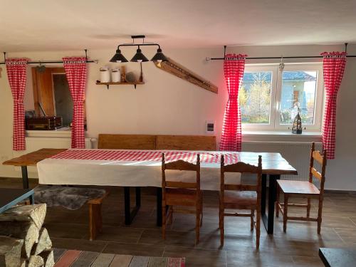 a dining room with a table and red curtains at Chata Studnička Šumiac in Šumiac