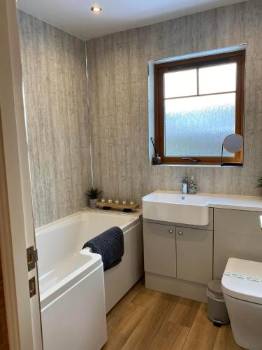 a bathroom with a tub and a sink and a toilet at The Nook Holiday Cottage in Aviemore