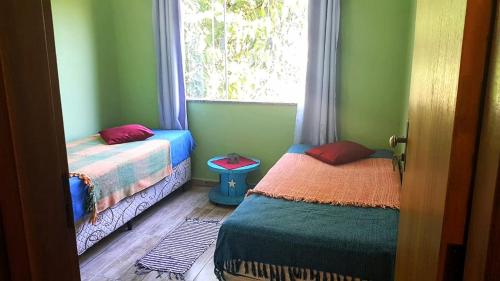 Duas camas num quarto com uma janela em Aconchegante Casa em São Lourenço