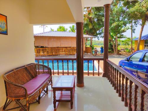 a balcony with a bench and a table and a car at Kayaloram Resort in Pūvār