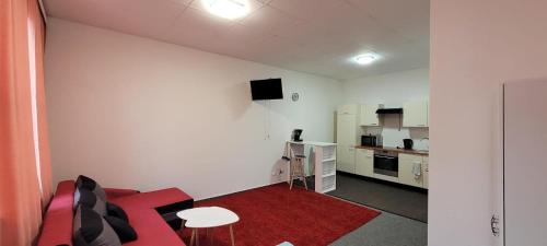 a living room with a red couch and a kitchen at Gästewohnung Kristall 3 in Salzwedel