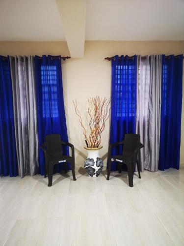 a room with blue curtains and two chairs and a plant at pié de la montaña in Bonao