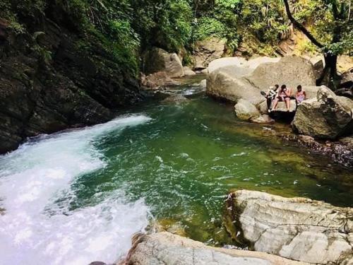 a group of people sitting on rocks in a river at pié de la montaña in Bonao