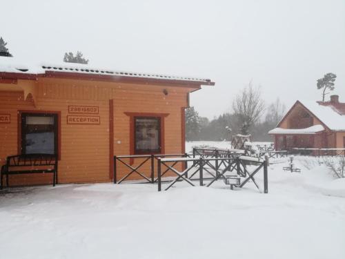 a building with tables in the snow in front of it at Oāze Smiltenē in Smiltene