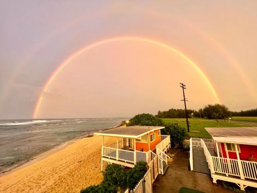 a rainbow over a beach with a house at Mokulē'ia Beach Houses at Owen's Retreat in Waialua