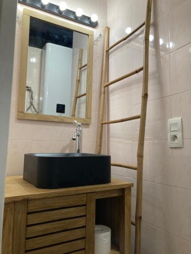 une salle de bain avec un lavabo noir et un miroir dans l'établissement Studio Banane avec sa terrasse, à Lorient