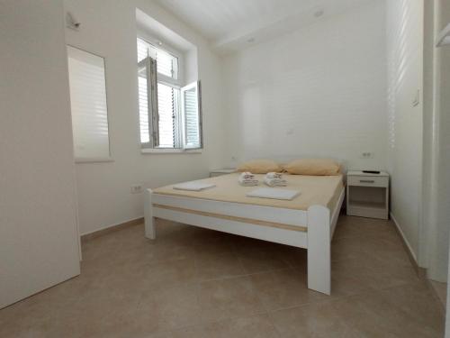 a white bedroom with a bed and a window at Dolce Far Niente in Herceg-Novi