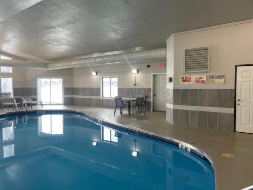 a swimming pool with a table and chairs in a building at Clarion Pointe Tomah in Tomah