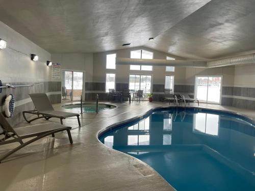 a pool in a building with chairs and a swimming pool at Clarion Pointe Tomah in Tomah