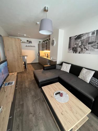 a living room with a black couch and a table at apartmán Jestřáb 14 in Janske Lazne