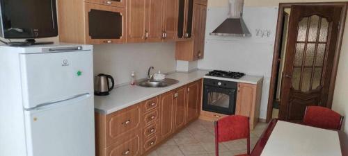 a kitchen with a white refrigerator and wooden cabinets at Spacious apartment at the foot of Mashuk mountain in Pyatigorsk