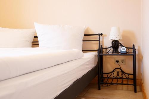 ein Bett mit weißer Bettwäsche und einer Lampe auf einem Beistelltisch in der Unterkunft Haus Uthlande Uthlande Whg 4 in Wyk auf Föhr