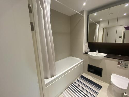 a bathroom with a tub and a toilet and a sink at London Dockside Apartment in London