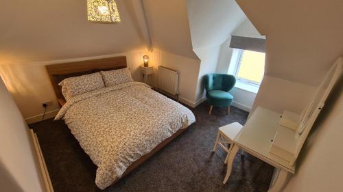 a small bedroom with a bed and a blue chair at Tawny Roost in Buxton