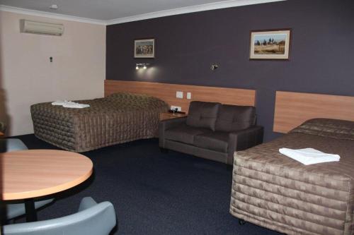 um quarto de hotel com duas camas e uma mesa e uma cadeira em SunPalms Motel em Rockhampton