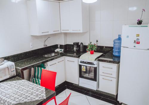 a kitchen with white cabinets and a white refrigerator at Próximo a praia das castanheiras, internet, cooler, cadeiras de praia,roupas de cama e banho in Guarapari