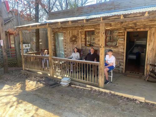 eine Gruppe von Personen, die auf der Veranda einer Hütte sitzen in der Unterkunft Acorn Hideaways Canton Old West Bunkhouse for 9 - Trail's End Corral in Canton