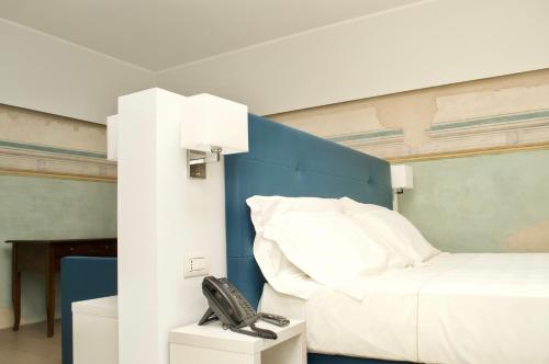 a bedroom with a bed with a phone next to it at Hotel Boutique Castiglione del Lago in Castiglione del Lago